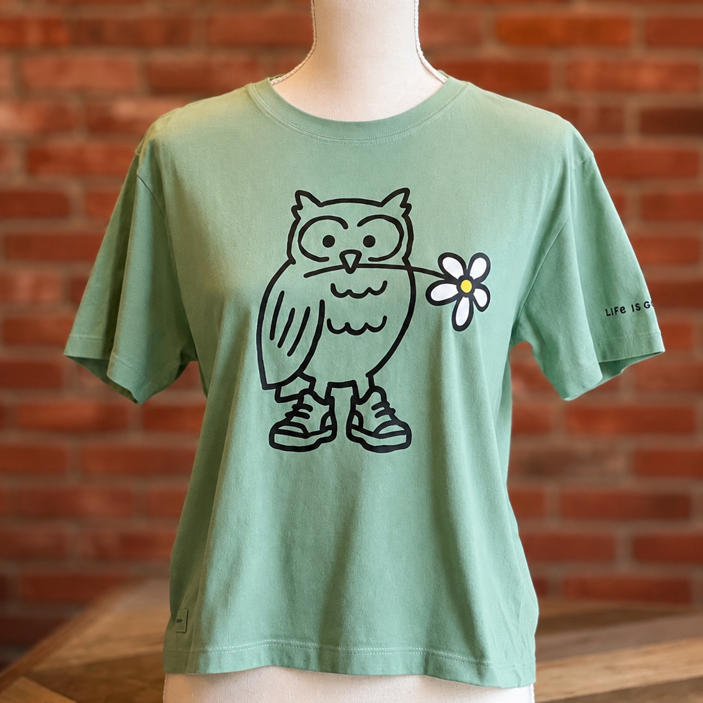 Green Life is Good T-shirt featuring a black outlined owl wearing sneakers and holding a white daisy, displayed on a mannequin.