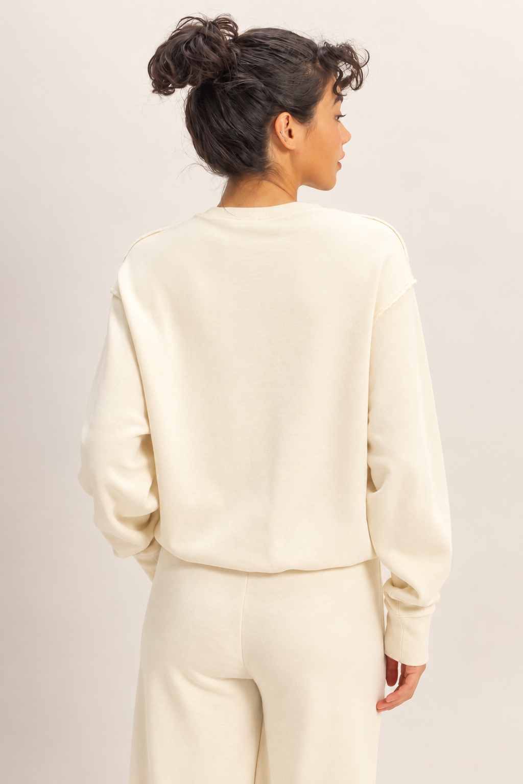 Back view of the Double Zero raw edge sweatshirt in Whip Cream with matching pants.