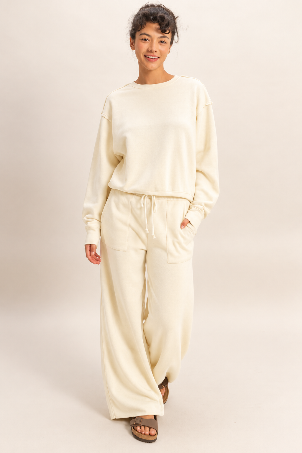 Model wearing the Double Zero raw edge sweatshirt in Whip Cream with matching wide-leg pants.