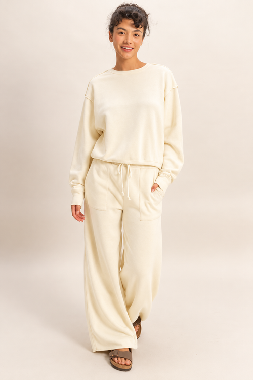 Model wearing the Double Zero raw edge sweatshirt in Whip Cream with matching wide-leg pants.