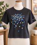 Life is Good women’s faded black cropped T-shirt featuring scattered blue and white daisies, displayed on a torso mannequin.