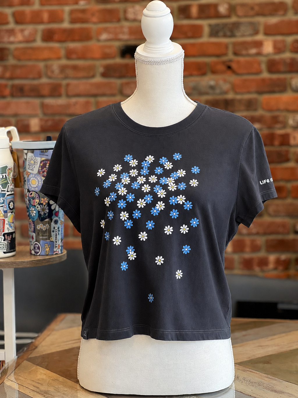 Life is Good women’s faded black T-shirt with scattered blue and white daisy print.