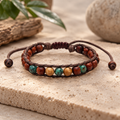 Lotus and Luna men’s Salty Grom bracelet with wood, green and tan beads on dark brown adjustable cord, displayed on a neutral stone surface.